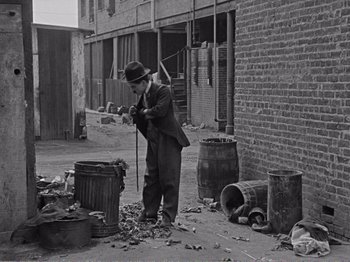 Movie still from “The Kid” (1921), directed by Charles Chaplin – An old photo of a man in a suit and a hat; Wide shot, High angle