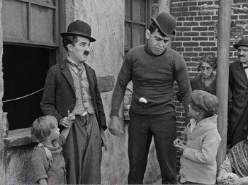 Movie still from “The Kid” (1921), directed by Charles Chaplin – A group of people standing next to each other; Medium shot, High angle