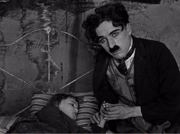 Movie still from “The Kid” (1921), directed by Charles Chaplin – An old photo of a man and a little girl; Medium shot, High angle