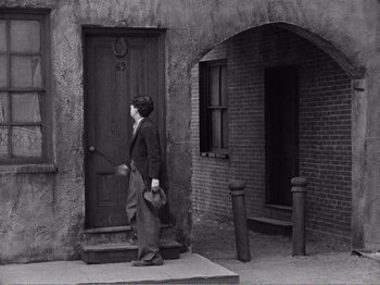 Movie still from “The Kid” (1921), directed by Charles Chaplin – An old photo of a woman walking down the street; Wide shot, High angle