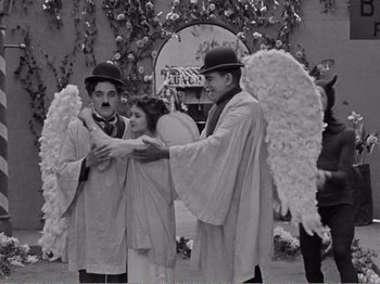 Movie still from “The Kid” (1921), directed by Charles Chaplin – A couple of men and a little girl dressed as angels; Wide shot, High angle