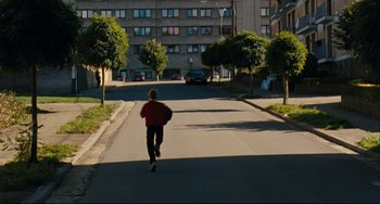 Movie still from “The Kid with a Bike” (2011), directed by Jean-Pierre Dardenne – A person running down the street in the middle of the day; Extreme Wide shot, High angle