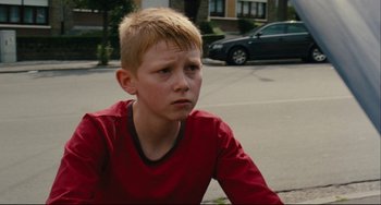 Movie still from “The Kid with a Bike” (2011), directed by Jean-Pierre Dardenne – A young boy sitting on the side of the street; Close Up shot, Low angle