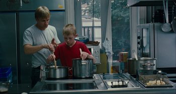 Movie still from “The Kid with a Bike” (2011), directed by Jean-Pierre Dardenne – A man and a boy cooking in a kitchen; Medium shot, Low angle