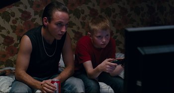 Movie still from “The Kid with a Bike” (2011), directed by Jean-Pierre Dardenne – Two young men sitting in front of a television; Medium shot, High angle