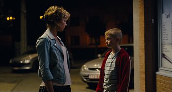 Movie still from “The Kid with a Bike” (2011), directed by Jean-Pierre Dardenne – A woman standing next to a young boy on a street; Medium shot, Over the shoulder angle