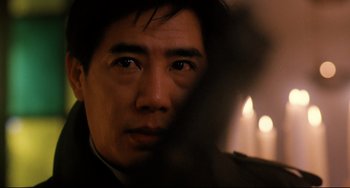 Movie still from “The Killer” (1989), directed by John Woo – A man's face in a dark room; Close Up shot, Over the shoulder angle