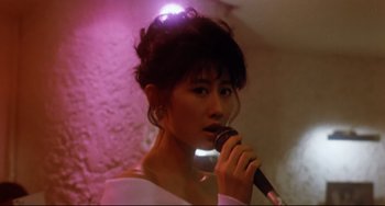 Movie still from “The Killer” (1989), directed by John Woo – A woman holding a microphone in her hand; Close Up shot, Low angle