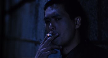 Movie still from “The Killer” (1989), directed by John Woo – A man is smoking a cigarette in a dark room; Close Up shot, Low angle