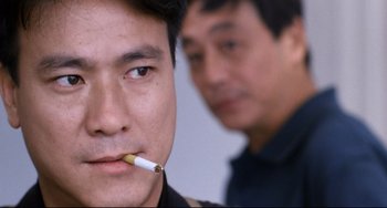 Movie still from “The Killer” (1989), directed by John Woo – A man with a cigarette in his mouth and another man with a cigarette in his mouth; Close Up shot, Over the shoulder angle