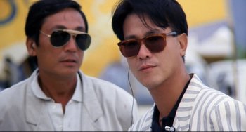 Movie still from “The Killer” (1989), directed by John Woo – Two men wearing sunglasses and one is listening to music with headphones; Close Up shot, Low angle