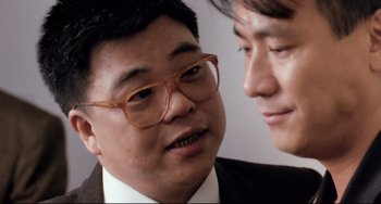 Movie still from “The Killer” (1989), directed by John Woo – Two asian men in suits and glasses talking; Close Up shot, Over the shoulder angle
