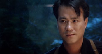 Movie still from “The Killer” (1989), directed by John Woo – A man's face in front of trees; Close Up shot, Low angle