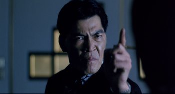 Movie still from “The Killer” (1989), directed by John Woo – A man in a suit and tie pointing at the camera; Close Up shot, Low angle