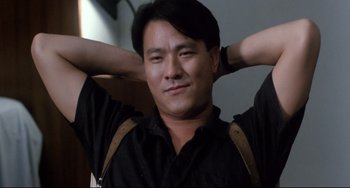 Movie still from “The Killer” (1989), directed by John Woo – A person sitting with his hands behind his head; Close Up shot, Low angle