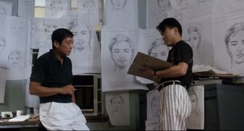 Movie still from “The Killer” (1989), directed by John Woo – Two men standing next to each other in front of a bunch of drawings; Medium shot, Over the shoulder angle
