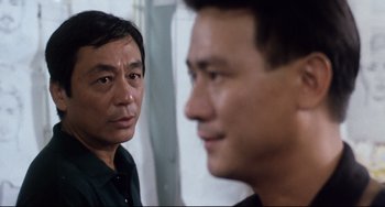 Movie still from “The Killer” (1989), directed by John Woo – Two men looking at each other in front of a wall; Close Up shot, Over the shoulder angle