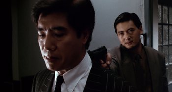 Movie still from “The Killer” (1989), directed by John Woo – Two men in suits and ties holding a gun; Medium shot, Over the shoulder angle