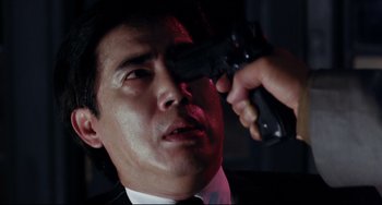 Movie still from “The Killer” (1989), directed by John Woo – A man holding a gun up to his eye; Close Up shot, Low angle
