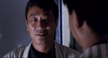 Movie still from “The Killer” (1989), directed by John Woo – A person wearing a white shirt; Close Up shot, Over the shoulder angle