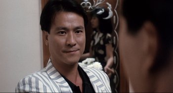 Movie still from “The Killer” (1989), directed by John Woo – A person wearing a suit; Close Up shot, Over the shoulder angle