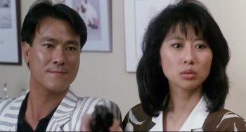 Movie still from “The Killer” (1989), directed by John Woo – A man and a woman are holding a remote control; Close Up shot, Low angle