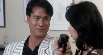 Movie still from “The Killer” (1989), directed by John Woo – A man and a woman are holding a gun; Close Up shot, Over the shoulder angle