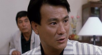 Movie still from “The Killer” (1989), directed by John Woo – A person wearing a striped shirt; Close Up shot, Over the shoulder angle