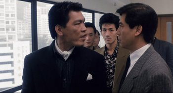 Movie still from “The Killer” (1989), directed by John Woo – A group of men standing next to each other in front of a window; Medium shot, Over the shoulder angle