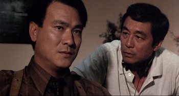 Movie still from “The Killer” (1989), directed by John Woo – Two asian men are sitting next to each other; Close Up shot, Over the shoulder angle