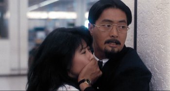 Movie still from “The Killer” (1989), directed by John Woo – A man and a woman hugging each other in a room; Close Up shot, Over the shoulder angle