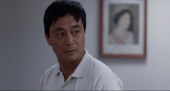 Movie still from “The Killer” (1989), directed by John Woo – A person wearing a white shirt; Close Up shot, Over the shoulder angle