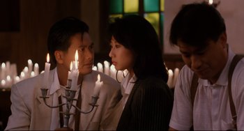 Movie still from “The Killer” (1989), directed by John Woo – A group of people that are standing in front of candles; Medium shot, Over the shoulder angle