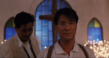 Movie still from “The Killer” (1989), directed by John Woo – A man standing next to another man in front of a cross; Close Up shot, Low angle