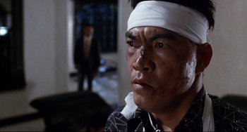 Movie still from “The Killer” (1989), directed by John Woo – A man with bandages on his head and a bandage on his face; Close Up shot, Low angle