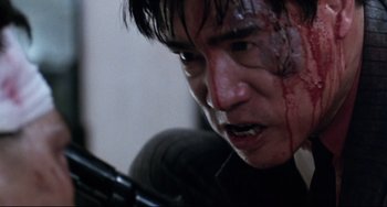 Movie still from “The Killer” (1989), directed by John Woo – A person holding a gun with blood all over his face; Close Up shot, Low angle
