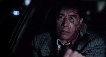 Movie still from “The Killer” (1989), directed by John Woo – A person in a car with blood all over his face; Close Up shot, Low angle