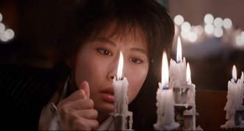 Movie still from “The Killer” (1989), directed by John Woo – A woman looking at candles in the dark; Close Up shot, Low angle