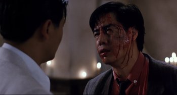 Movie still from “The Killer” (1989), directed by John Woo – A man with blood all over his face and neck; Close Up shot, Over the shoulder angle