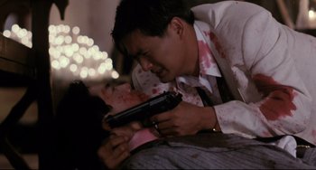 Movie still from “The Killer” (1989), directed by John Woo – A man holding a gun over a woman's face; Close Up shot, Over the shoulder angle