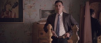 Movie still from “The Killer Inside Me” (2010), directed by Michael Winterbottom – A man in a suit and tie standing in front of a table; Medium shot, Low angle