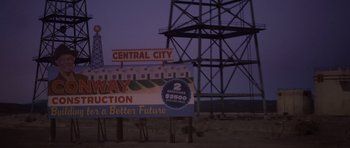Movie still from “The Killer Inside Me” (2010), directed by Michael Winterbottom – A sign that reads " central city " and " freeway junction "; Extreme Wide shot, High angle