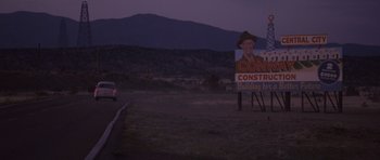 Movie still from “The Killer Inside Me” (2010), directed by Michael Winterbottom – A car driving down a road next to a construction sign; Extreme Wide shot, Low angle
