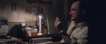 Movie still from “The Killer Inside Me” (2010), directed by Michael Winterbottom – A man sitting at a table with a cigarette in his hand; Close Up shot, High angle