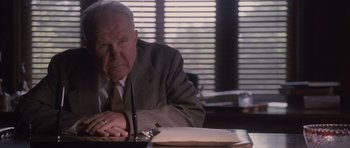 Movie still from “The Killer Inside Me” (2010), directed by Michael Winterbottom – An older man sitting at a table with a pen and paper; Close Up shot, Low angle
