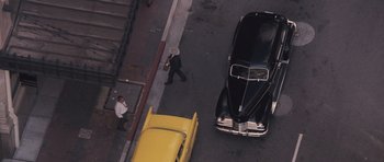 Movie still from “The Killer Inside Me” (2010), directed by Michael Winterbottom – An aerial view of a man walking down the street; Extreme Wide shot, Overhead angle