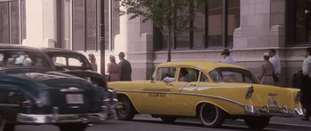 Movie still from “The Killer Inside Me” (2010), directed by Michael Winterbottom – An old yellow taxi cab parked on the side of the street; Wide shot, Over the shoulder angle