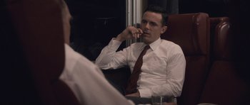 Movie still from “The Killer Inside Me” (2010), directed by Michael Winterbottom – A man sitting in a chair talking on the phone; Medium shot, Over the shoulder angle