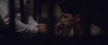 Movie still from “The Killer Inside Me” (2010), directed by Michael Winterbottom – A man smoking a cigarette while another person holds a cigarette; Close Up shot, High angle