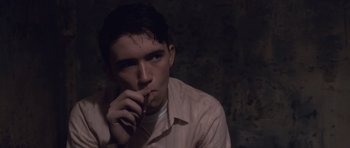 Movie still from “The Killer Inside Me” (2010), directed by Michael Winterbottom – A man in a pink shirt is holding a pen in his mouth; Close Up shot, High angle